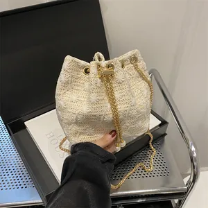 Straw woven bucket bag with elegant 3D floral accents and gold chain strap for women