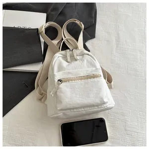 Close-up of white mini canvas backpack with pleated texture and adjustable straps