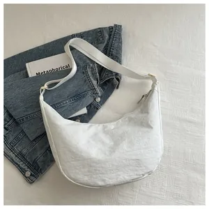 Detail van witte nylon halve maan tas met brede stoffen riem op gaas ondergrond