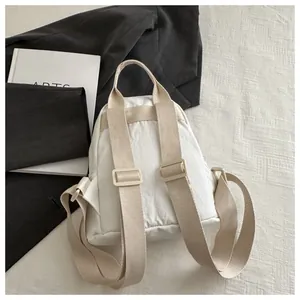 Detail view of the white canvas backpack back with adjustable straps and top handle