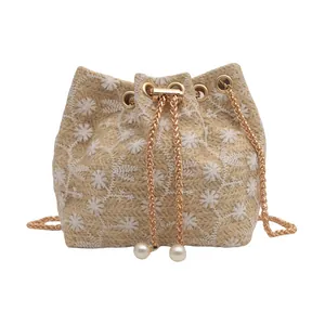 Straw bucket bag with white floral embroidery, gold chain strap and pearl drawstring detail