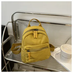 Detailed close-up of a bright yellow mini canvas backpack on a metal mesh chair