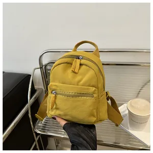Close-up of yellow canvas mini backpack showing durable texture and double zippers