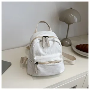Mini beige canvas backpack with dual zippers shown in a cozy home lifestyle setting