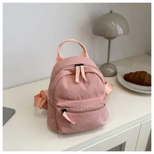 Detailed view of pink mini canvas backpack with zippers on a minimalist desk setup