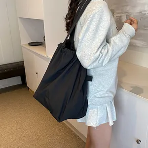 Grande borsa a tracolla in nylon nero con coulisse e design minimalista dall'effetto lucido