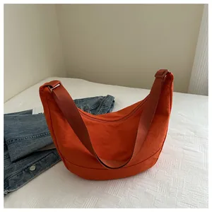 Detail van oranje nylon halvemaantas met stoftextuur en een verstelbare schouderriem