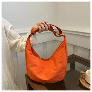 Detailweergave van een oranje hobo-tas van waterbestendig nylon met verstelbare schouderband