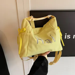 Gele canvas draagtas met borduursel en strik vastgehouden door een fotomodel