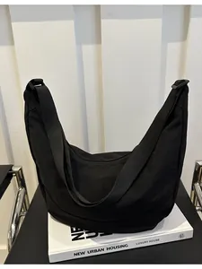Minimalistische zwarte halve maan schoudertas met verstelbare riem op wit decor