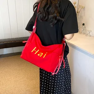 Large red nylon crossbody tote bag with yellow Hai embroidery and pink adjustable strap