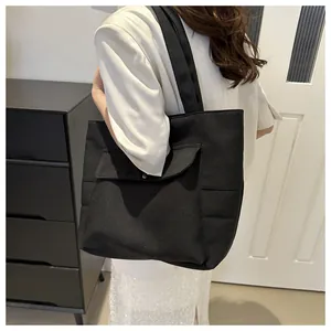 Vue détaillée du sac cabas en toile noire avec grande poche à rabat et poches latérales