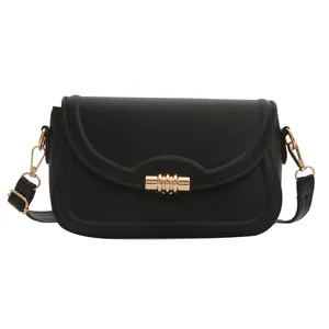 Minimalist black crossbody bag with wavy flap edge and gold cylindrical metal buckle