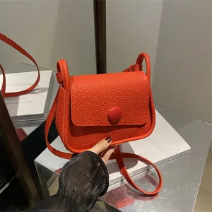 Minimalist red pebble leather crossbody square bag with a matching round buckle