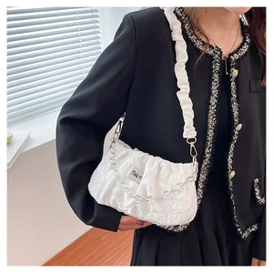Detail of white pleated cloud bag with silver floral chain and textured fabric finish