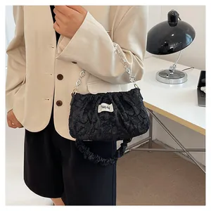 Detail of black pleated cloud bag featuring silver metal chain and branding label