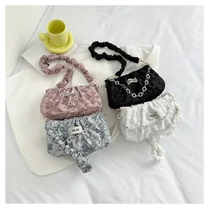 Detail of four pleated cloud bags in pink, black, grey, white with flower chain charms