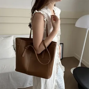 Brown vintage leather tote bag with white stitching shown on a model in home setting