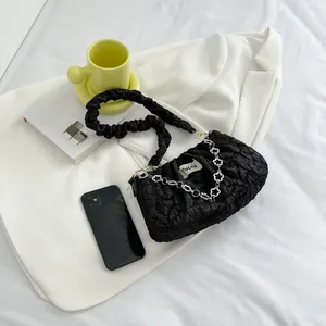 Minimalist black pleated shoulder bag with a silver floral chain and ruched strap design