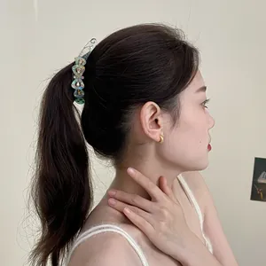 Barrette banane à fleurs bleues irisées portée sur un mannequin en queue de cheval