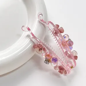 Pink resin banana hair clip with floral bead embellishments on a white background