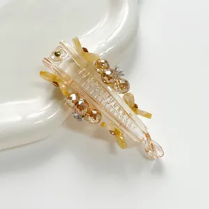 Détails d'une pince banane en résine champagne avec perles taillées et fleurs ambrées
