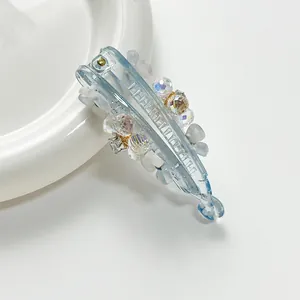 Detail of light blue banana hair clip with sparkling crystals and white floral accents