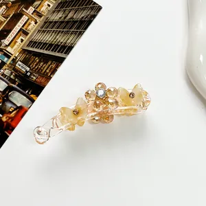 Détail d'une pince banane avec fleur en cristal ambré et papillons en résine crème