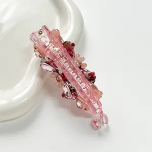 Detailed view of pink resin banana clip with crystal flowers and rhinestones