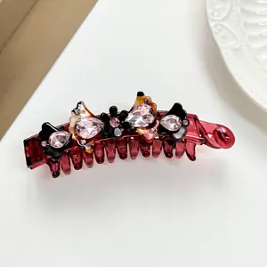 Close-up of a banana clip with dark red resin and sparkling crystal flower rhinestones