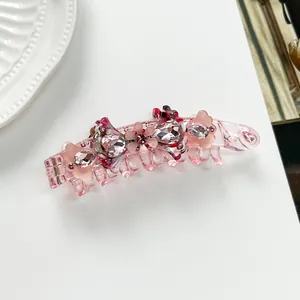 Macro detail of pink acetate banana clip with sparkling crystals and floral accents