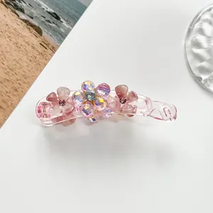 Detailed macro view of a pink resin banana clip with sparkling crystal flower decorations