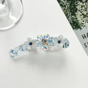 Detail showing blue resin banana clip with floral rhinestone and pearl accents
