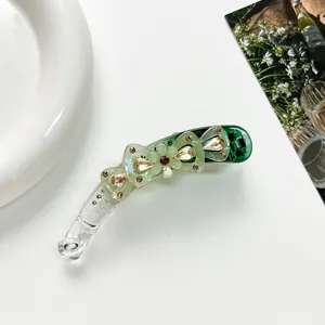 Vue détaillée d'une pince banane en résine verte avec nœud et strass champagne