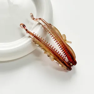 Amber banana hair clip with floral rhinestones on white ceramic tray background