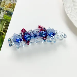 Detail of banana clip with blue rhinestones and purple floral accents on white background