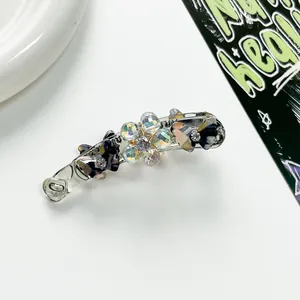Détail d'une pince banane incurvée avec des fleurs en cristal irisé et papillons