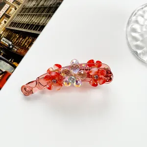Macro detail of pink resin banana clip featuring crystal flowers on white desk