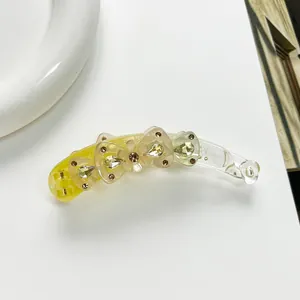 Détail d'une pince banane avec nœuds jaunes dégradés et pierres précieuses serties