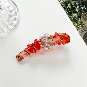 Détail de la barrette banane rouge translucide avec motifs papillons et fleurs en cristal
