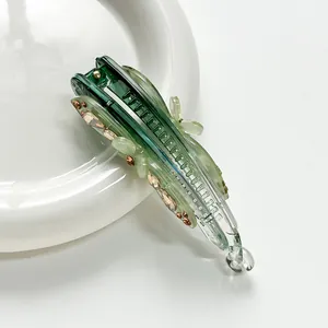 Detail of green banana hair clip with amber rhinestones on white ceramic plate