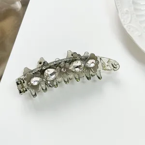 Detailed close-up of acetate banana clip with sparkling rhinestone flower and crystal accents