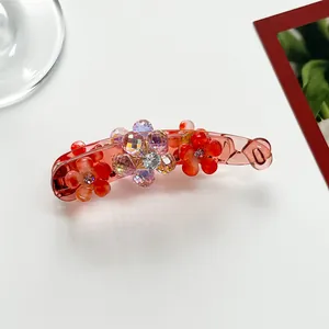 Detail of red flower banana clip with sparkling multi-colored beads and translucent finish