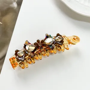 Macro shot of amber acetate banana clip with rhinestone flower and brown crystal bow