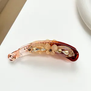 Detail of amber resin banana hair clip with floral accents and sparkling rhinestones