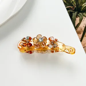 Close-up of amber banana hair clip with crystal flower beads on a white background