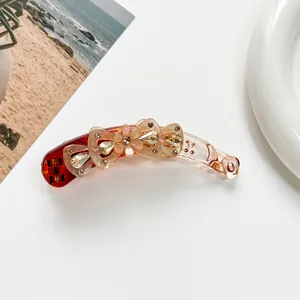 Détail d'une pince à cheveux banane fleurie en acrylique dégradé rouge avec strass