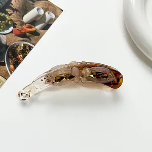 Detail of amber banana hair clip with 3D floral accents and sparkling rhinestones