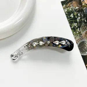 Detail of banana clip featuring shimmering rhinestones and a pearlescent floral motif