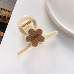 Détail d'une pince à cheveux fleur 7cm avec texte Barrette La France sur résine crème